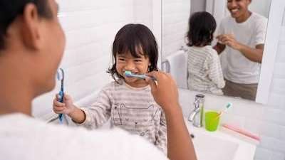 Dad helping young asian girl brush her teeth, palos heights il