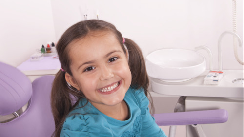 Happy young girl smiling in a pediatric dental chair during a dental visit
