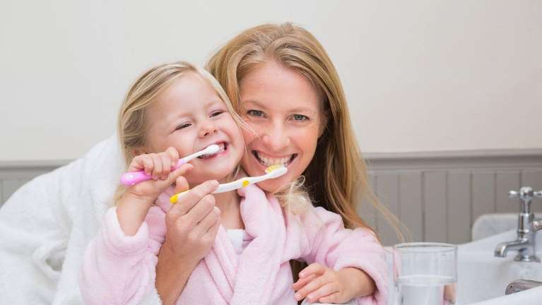 A mother and daughter brushing their teeth
