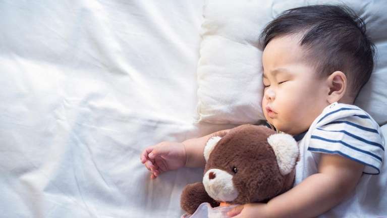 Young asian baby sleeping with a baby bear, palos heights il
