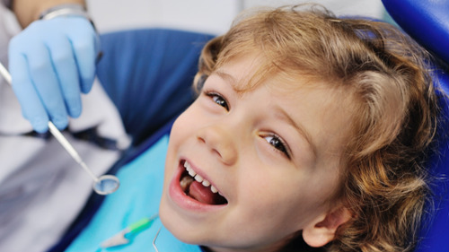 Smiling young child in dental chair during pediatric dental exam in Oak Forest